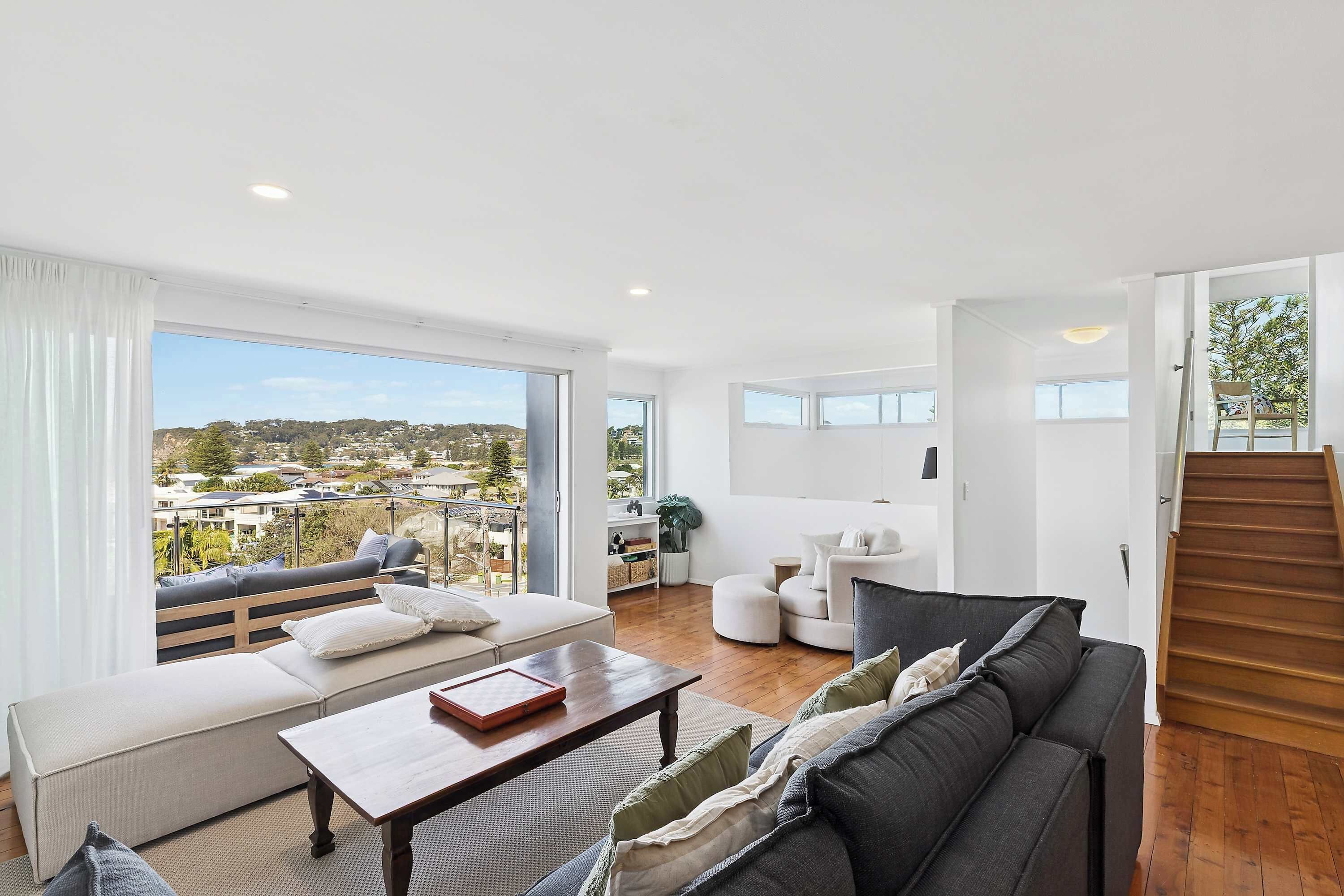 A spacious living area with a sofa, a coffee table, and a view of a balcony.