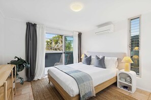Un dormitorio con cama, lámpara de noche y una mesita de noche blanca.
