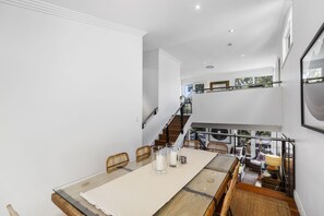 A dining area with a long table, chairs, and a staircase leading to an upper level.