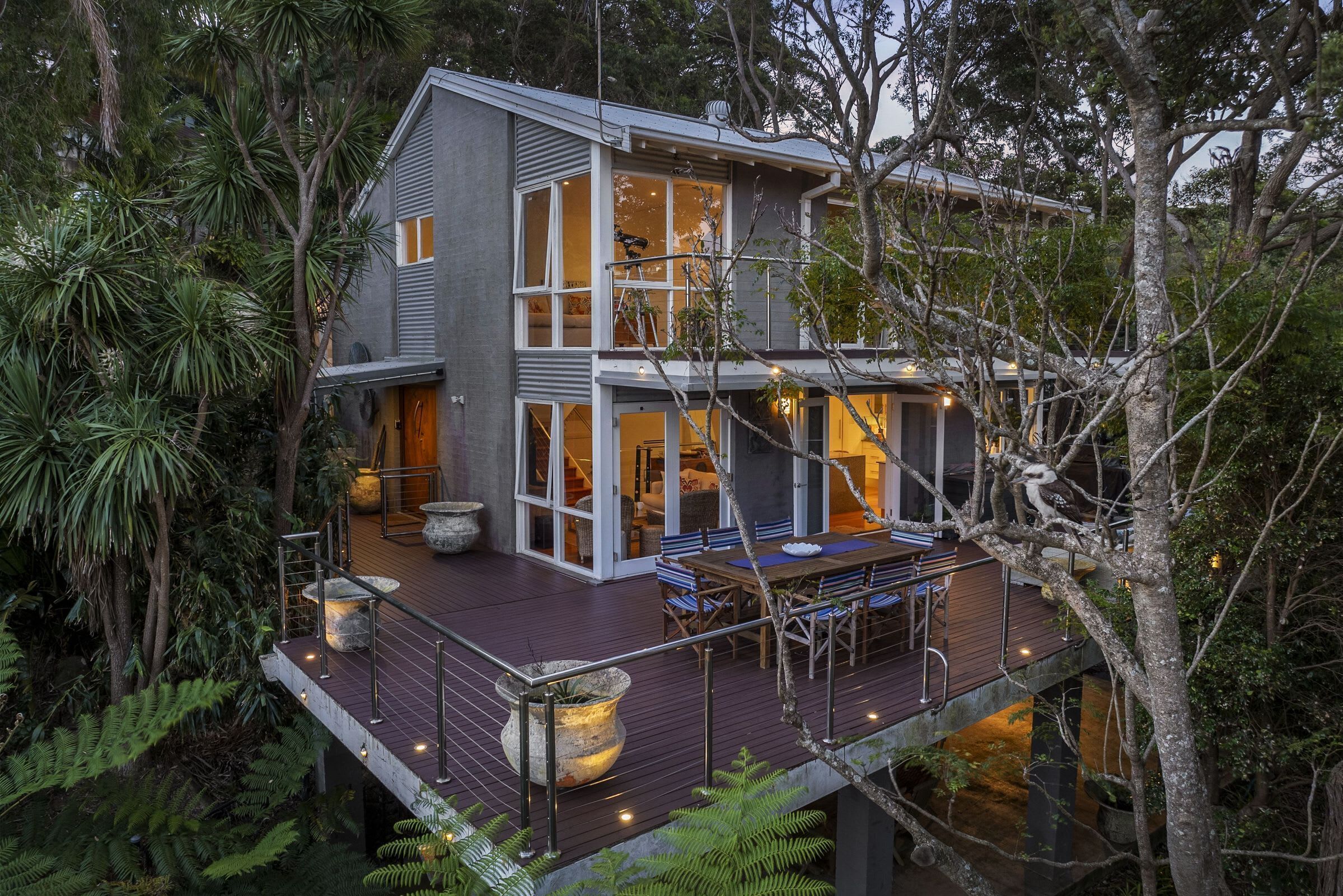 A modern two-story house with large windows, a deck, and a staircase.