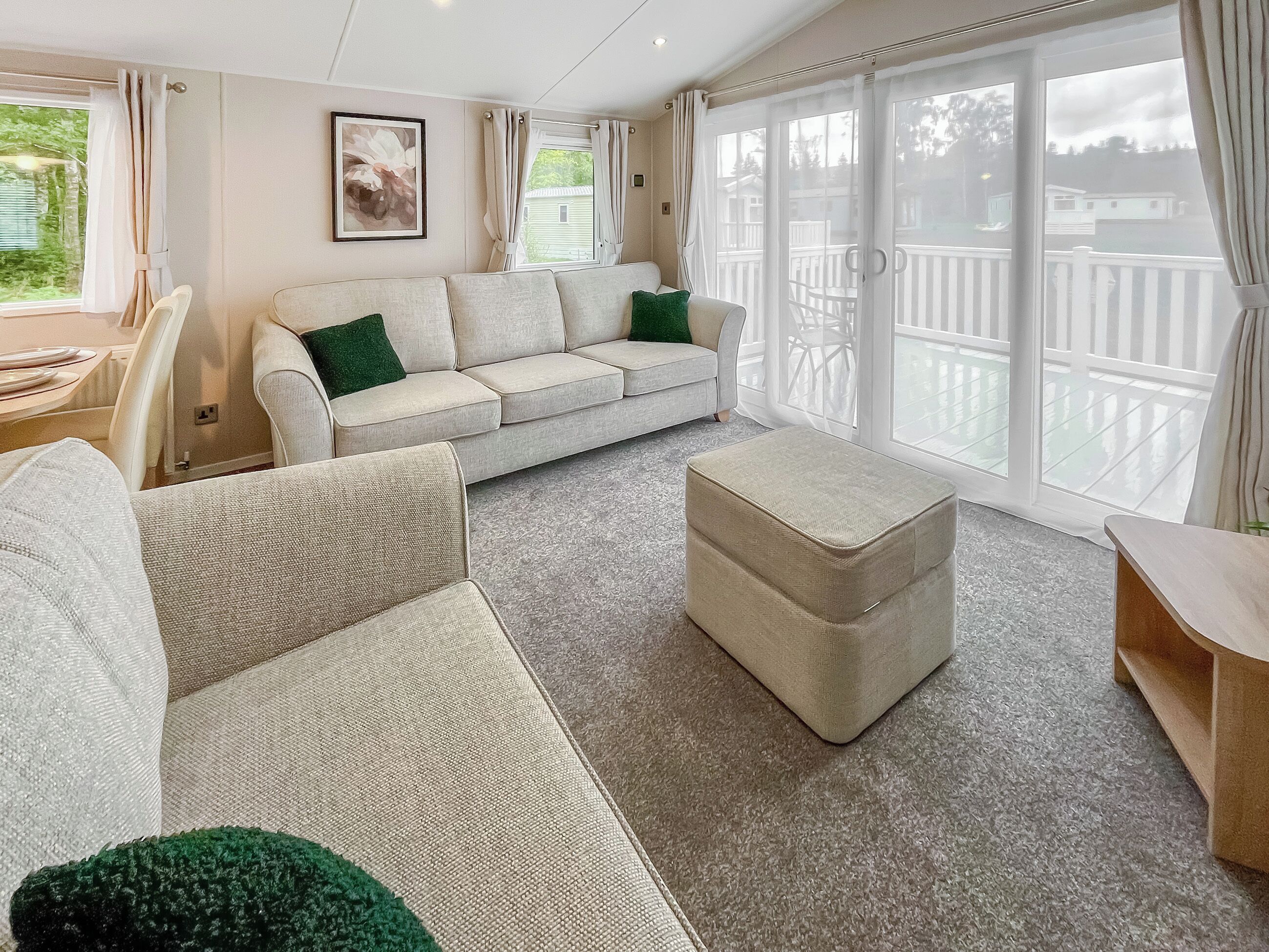 A spacious living room with a large sofa, a matching ottoman, and a dining area with a table and chairs.