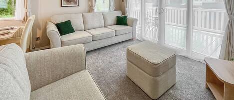 A spacious living room with a large sofa, a matching ottoman, and a dining area with a table and chairs.