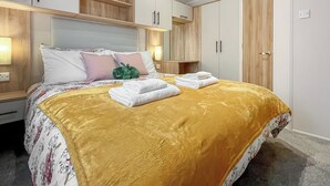 Habitación de hotel moderna con una cama grande, cabecera de madera, armario empotrado y lámparas de noche.