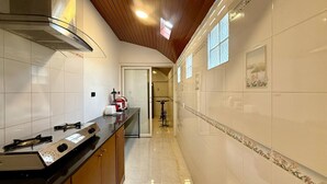 A modern kitchen with a stainless steel range hood, a countertop with a coffee maker, and a bicycle in the background.