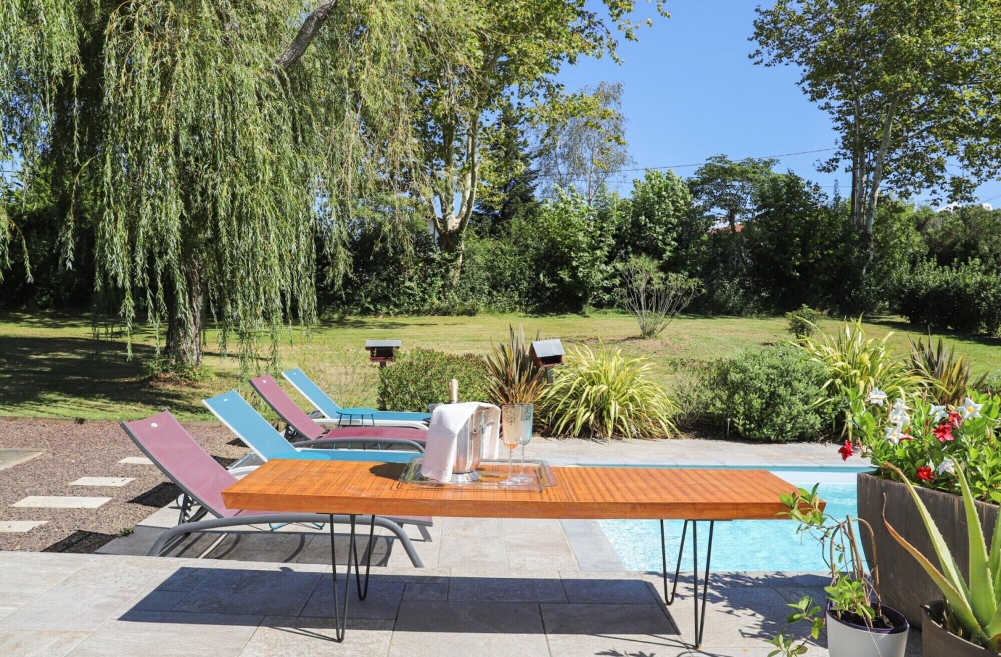 A poolside area with lounge chairs, a table, and a small pool.