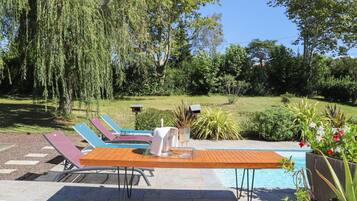 A poolside area with lounge chairs, a table, and a small pool.