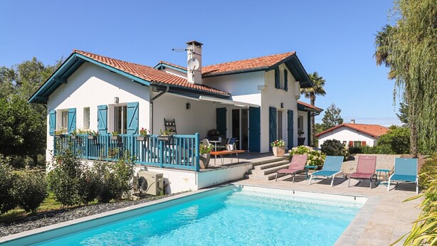 Une maison à deux étages avec une piscine, un patio couvert et un jardin.