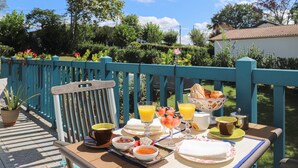 Une table dressée à l’extérieur avec des aliments pour le petit-déjeuner, notamment du pain, des fruits et des boissons.