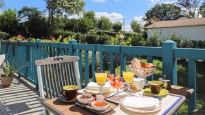 Une table dressée à l’extérieur avec des aliments pour le petit-déjeuner, une chaise et une clôture bleue.