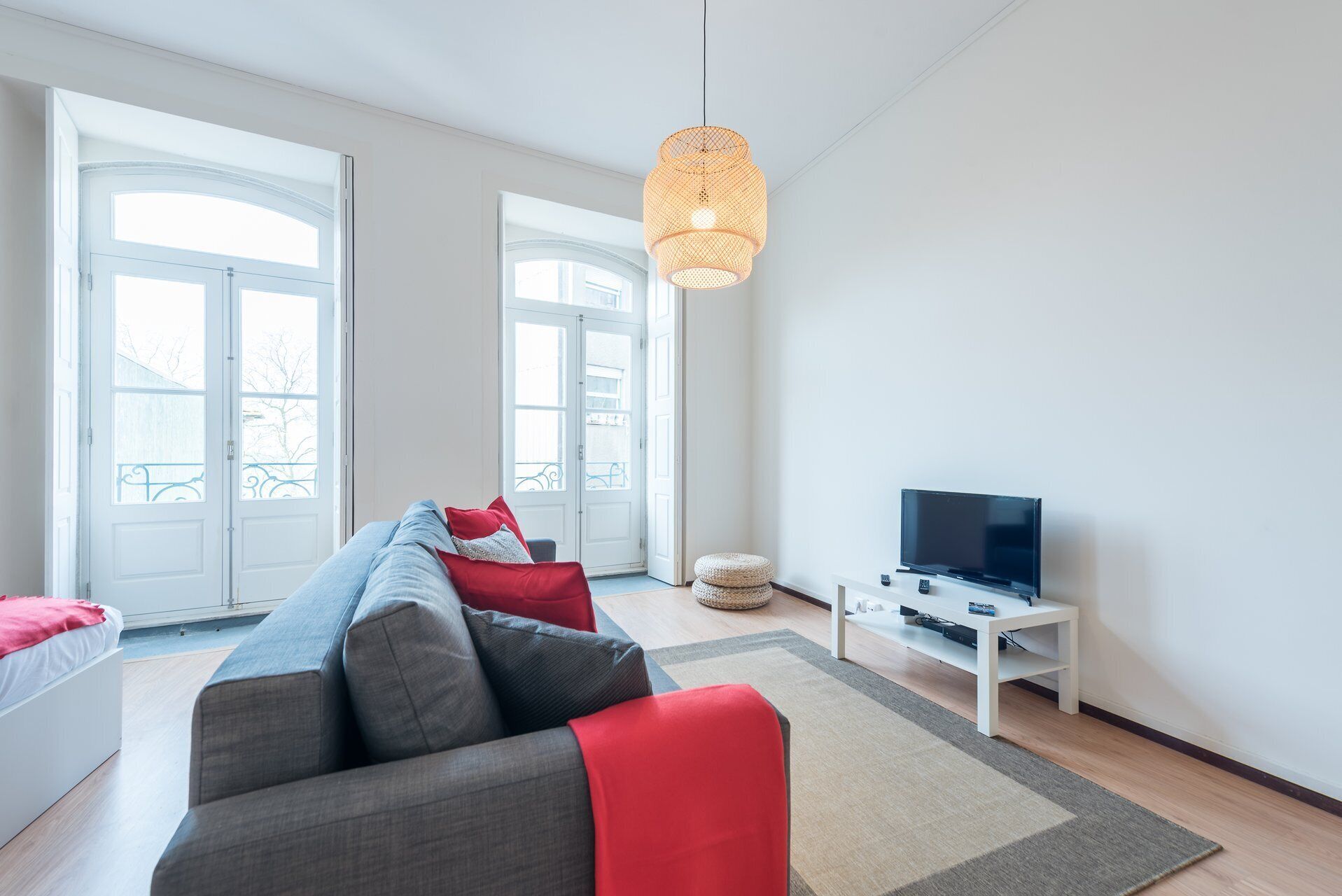 Una sala de estar moderna con un sofá, un televisor y una lámpara colgante.