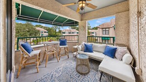 A covered outdoor seating area with wicker furniture, a ceiling fan, and a view of neighboring houses. - Bright Modern Pet Friendly Villa (Hilton Head Island)