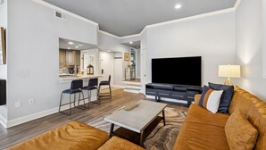 A modern living room with a sofa, TV, and dining area. - Bright Modern Pet Friendly Villa (Hilton Head Island)
