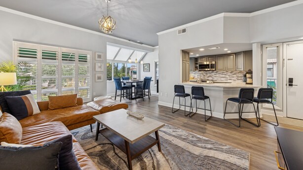 A spacious living room with a brown leather sofa, a wooden coffee table, and a large window with blinds. - Bright Modern Pet Friendly Villa (Hilton Head Island)