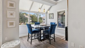 A dining area with a glass table, four blue chairs, and pendant lights. - Bright Modern Pet Friendly Villa (Hilton Head Island)
