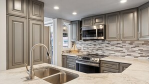 A modern kitchen with a double sink, stainless steel appliances, and a tiled backsplash. - Bright Modern Pet Friendly Villa (Hilton Head Island)