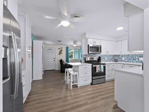 A modern kitchen with white cabinets, a stainless steel refrigerator, a microwave, and a stove. - Tranquil & Spacious Heated Pool, Hot Tub, Parking (Englewood)