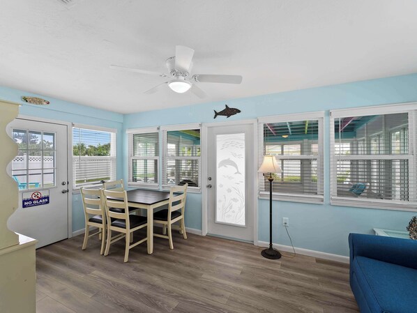 A room with a dining table, chairs, a ceiling fan, and a view of the outside.