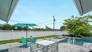 A patio area with a pool, white chairs, and a table. - Tranquil & Spacious Heated Pool, Hot Tub, Parking (Englewood)