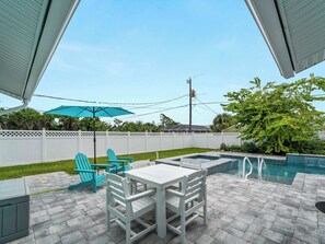Un espace patio avec une piscine, des chaises blanches et une table.