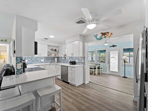 A modern kitchen with white cabinetry, a blue and white backsplash, and a central island. - Tranquil & Spacious Heated Pool, Hot Tub, Parking (Englewood)