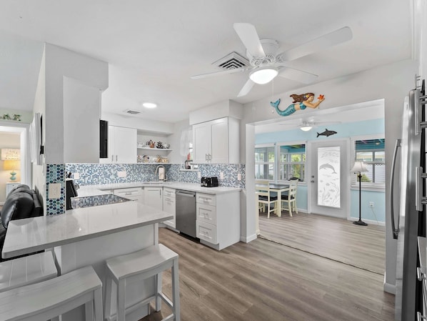 A modern kitchen with white cabinetry, a blue and white backsplash, and a central island.