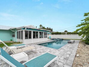 A pool area with lounge chairs and a covered patio.