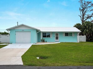 A single-story house with a garage, a front yard, and a palm tree.