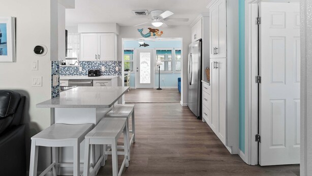 A modern kitchen with white cabinets, a blue backsplash, and a central island with benches. - Tranquil & Spacious Heated Pool, Hot Tub, Parking (Englewood)