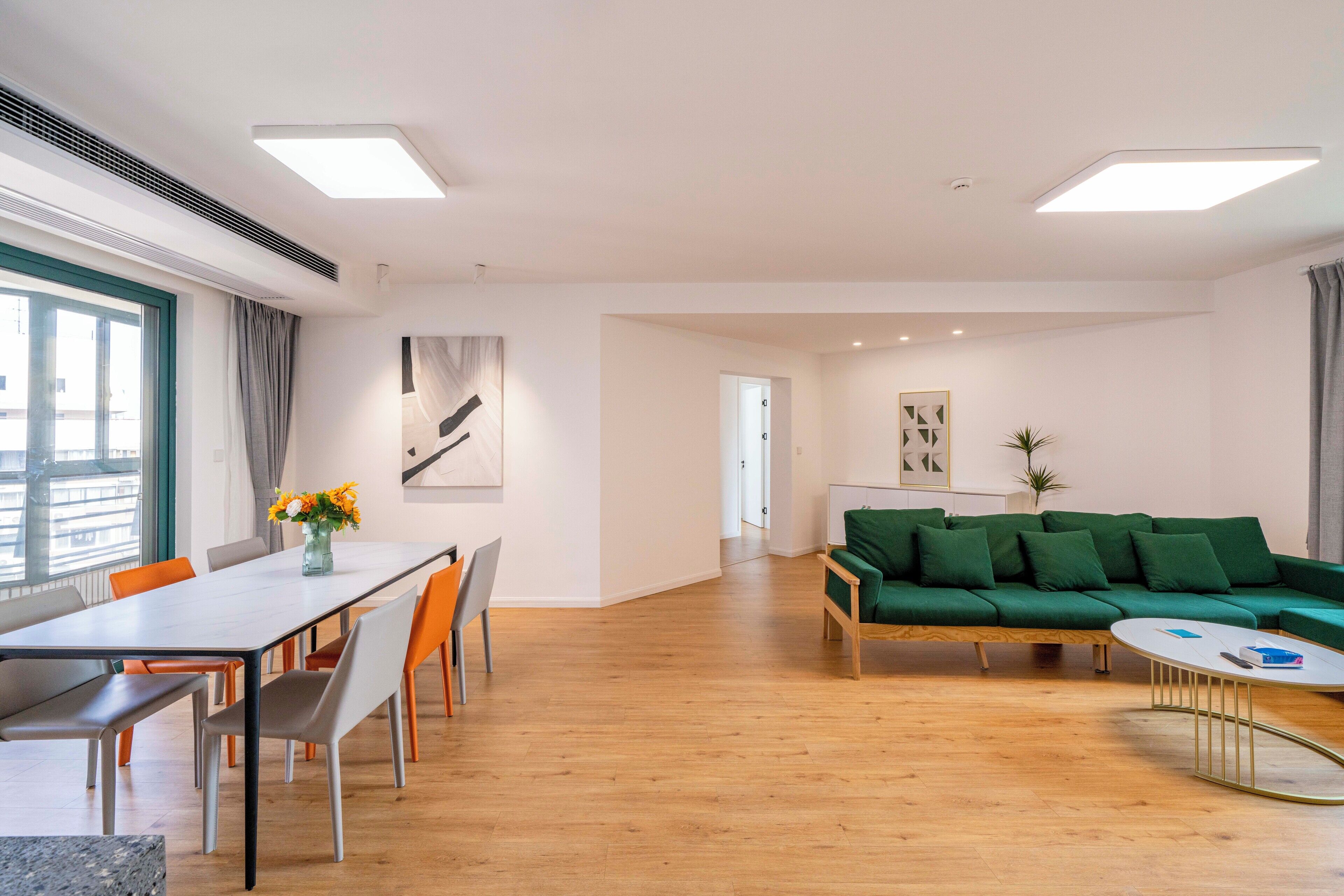 Una sala de estar moderna con comedor, un sofá verde y una mesa de centro de madera.