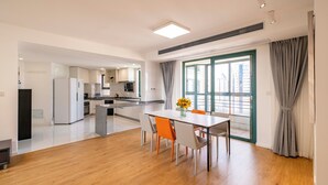A modern apartment with a dining area, kitchen, and large windows.