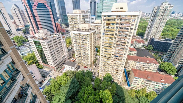 A high-rise building with multiple floors, surrounded by other tall buildings and greenery.