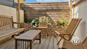 Eine Holzterrasse mit Tisch und zwei Stühlen, eine Ziegelwand und ein Holzzaun.