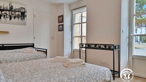 Ein Schlafzimmer mit zwei Betten, einem großen Fenster und einem Stadtbild an der Wand.