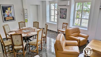 Un comedor con una mesa redonda, sillas y un sofá. Se ven ventanas con vistas a árboles y edificios.