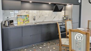 A modern kitchen with dark cabinetry, a marble backsplash, and a built-in oven. - Modern cottage in Louverné, sleeps 6-8, pets allowed, parking (Louverné)