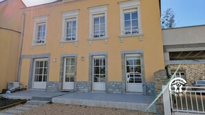 A two-story building with a yellow facade, white windows, and stone accents around the doors and windows. - Modern cottage in Louverné, sleeps 6-8, pets allowed, parking (Louverné)