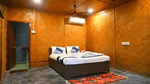 A bedroom with a bed, a ceiling fan, an air conditioning unit, and a patterned rug. - Crystal Andaman Resort (Port Blair)