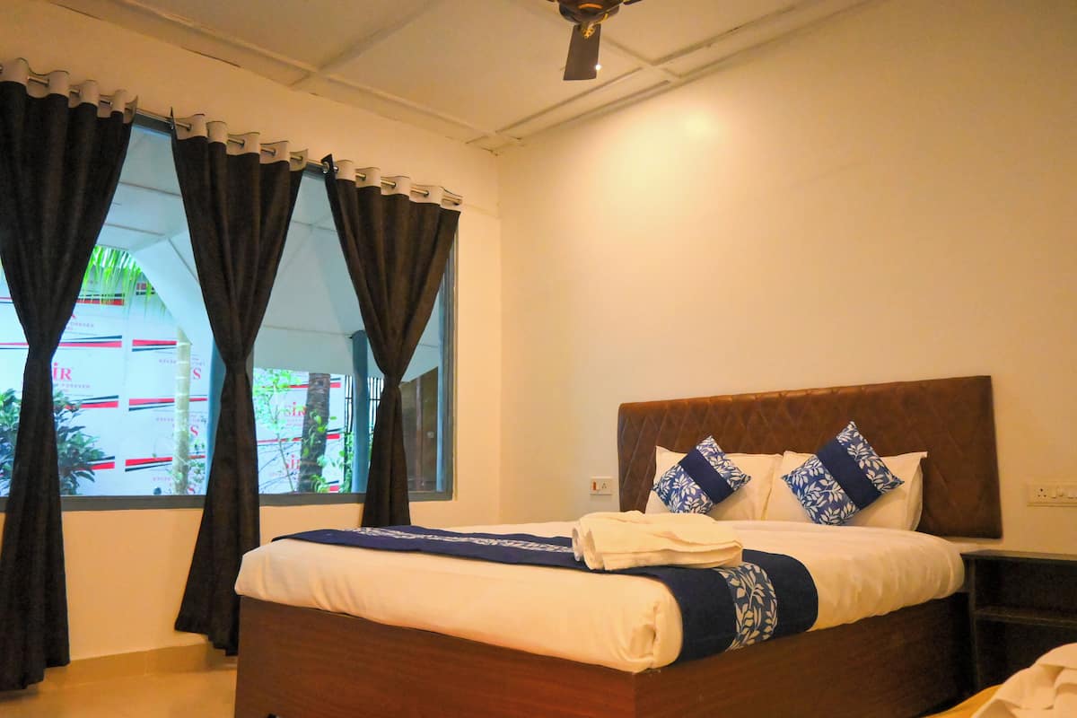 A neatly made bed with a wooden headboard, a bedside table, and a window with curtains.