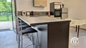 A modern kitchen with a large island, bar stools, a microwave, and a refrigerator. - Comfortable cottage for 6 with spacious terrace (Saint-Michel-de-la-Roë)