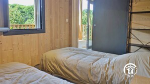 Une chambre avec deux lits, une fenêtre et une porte donnant sur une terrasse extérieure.