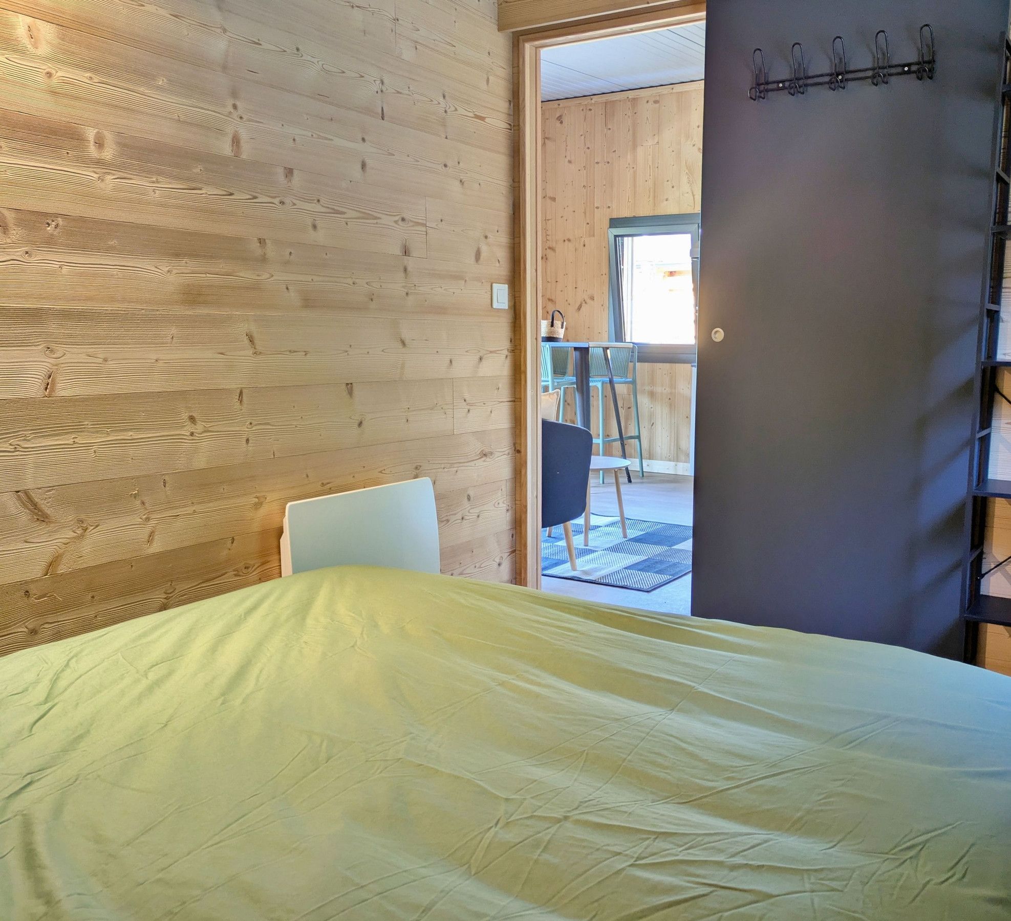 Una habitación con cama, una silla y vistas a un espacio exterior con mesa y sillas.