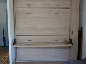 Una habitación con armario empotrado, una mesita y un banco.
