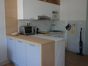 Una cocina compacta equipada con microondas, tostadora y lavabo.
