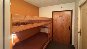 Une chambre avec un lit superposé, une porte et une lampe.