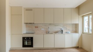 A modern kitchen with white cabinets, a built-in oven, and a marble backsplash.