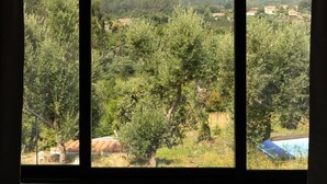 A room with large windows offering a view of a green landscape with trees and hills. - Quinta do Socalco (Caminha)