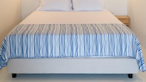 A bedroom with a wooden ceiling, two wall-mounted lights, a bed with a striped bedspread, and a nightstand with a lamp. - Quinta do Socalco (Caminha)