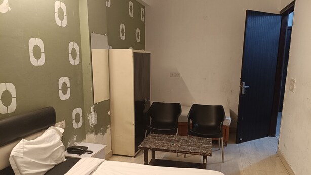 Een hotelkamer met een bed, een bureau, twee stoelen, een kledingkast en een deur.