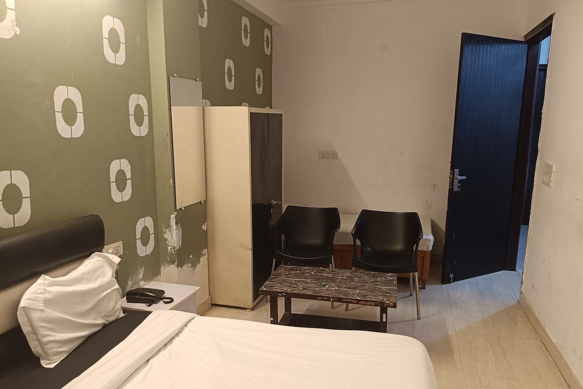 Una habitación de hotel con cama, escritorio, dos sillas, armario y puerta.