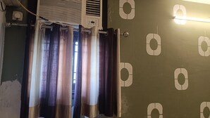 Een kamer met een wandairconditioner, een gordijnroede met gordijnen, en een muur met ronde patronen.